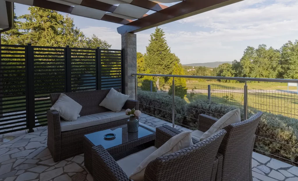 Custom black geometric privacy screen wall enclosing covered patio with outdoor sectional sofa