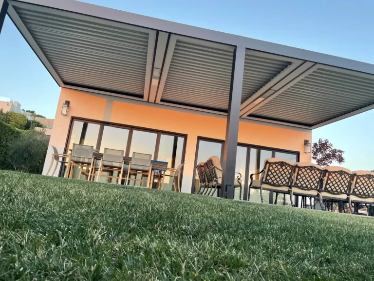Black motorized louvered roof pergola covering an elevated outdoor patio lounge