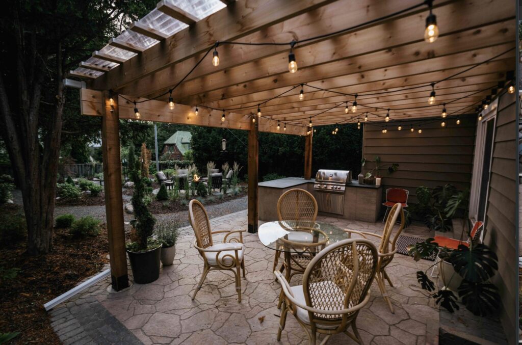 Custom wood pergola with string bistro lighting, patio seating, and built-in outdoor kitchen island
