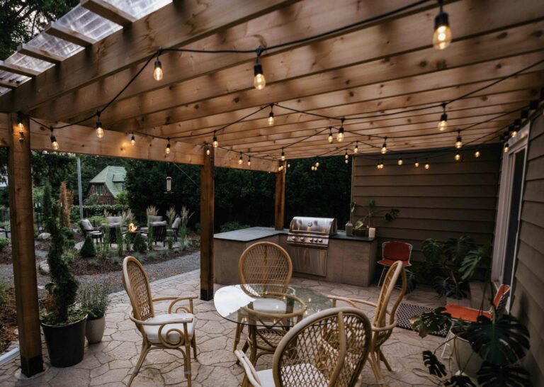 Custom covered outdoor living space with wood ceiling, outdoor kitchen, bar seating, and dining area for backyard entertaining.