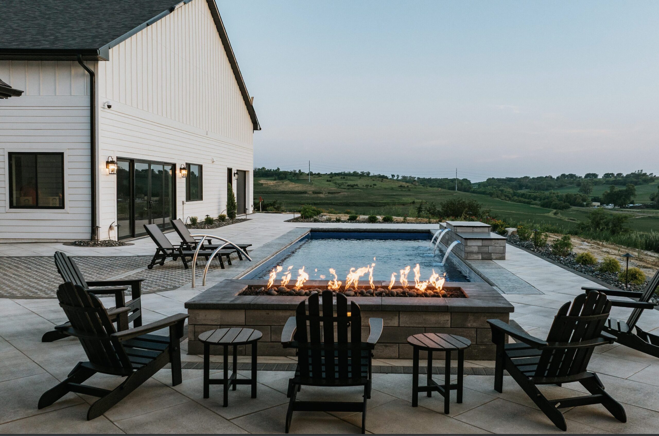 Modern backyard fire pit patio lounge overlooking scenic landscape at dusk