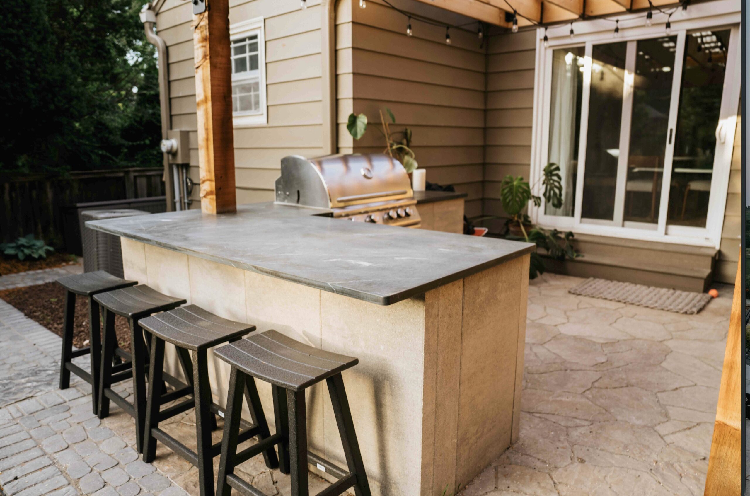 Custom outdoor kitchen with stainless steel grill and built-in island under a modern covered patio pavilion