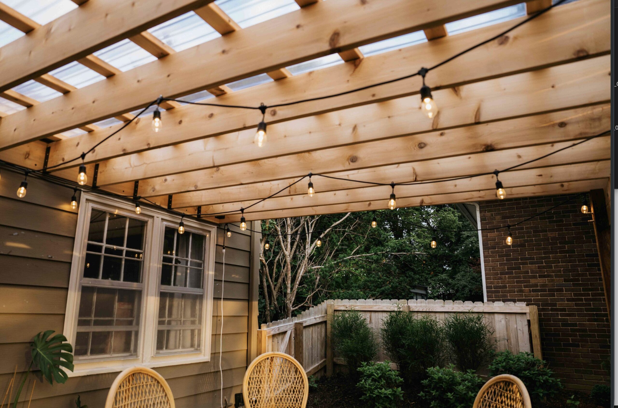 Custom wood patio pergola with integrated privacy wall and outdoor seating installed by professional landscaping contractor