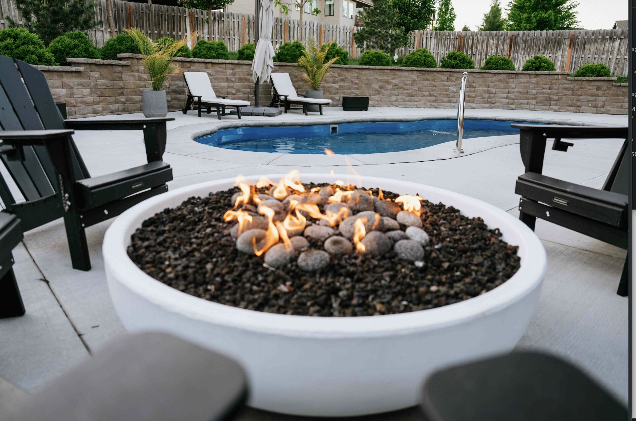Gas outdoor fireplace feature set on custom stone patio for four-season backyard outdoor living