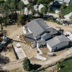 Aerial view of residential property during backyard pool excavation and hardscape build