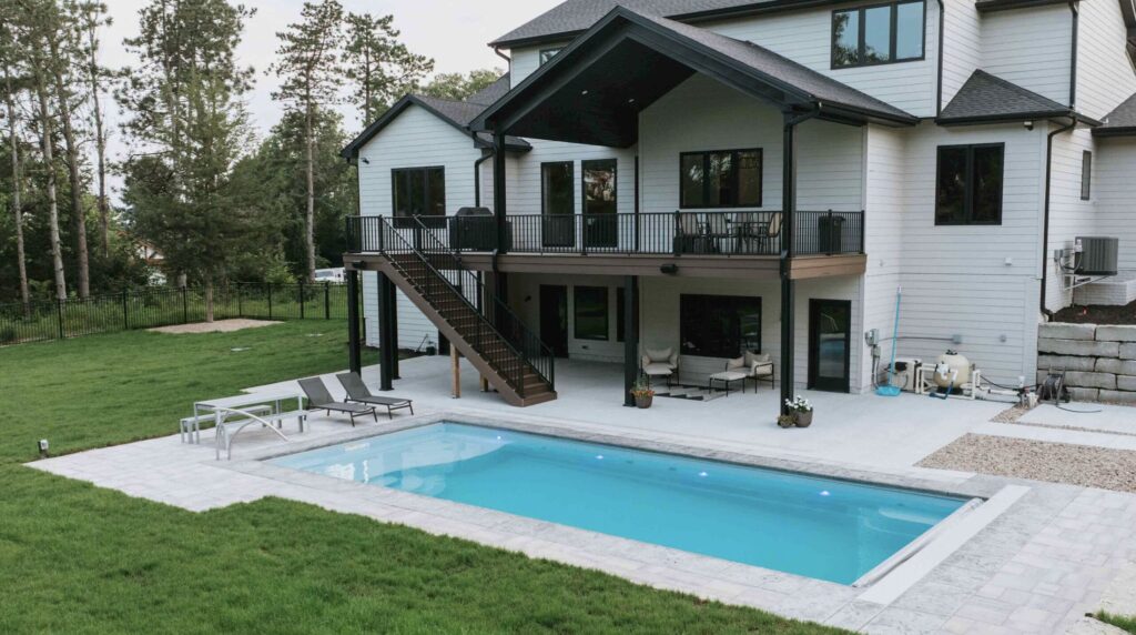 Modern custom home with elevated deck overlooking backyard inground swimming pool