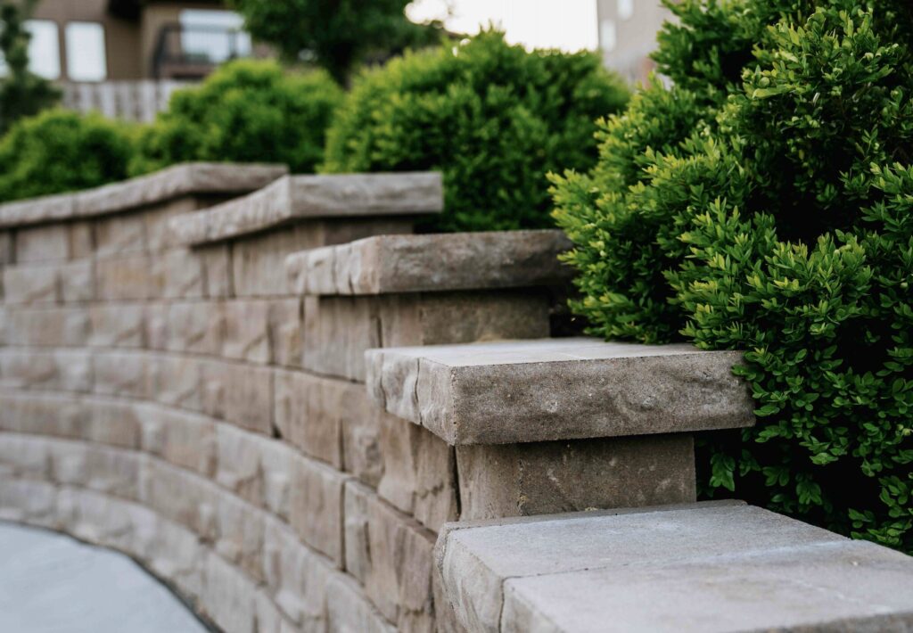 Tiered block retaining wall installation integrated with garden plant beds