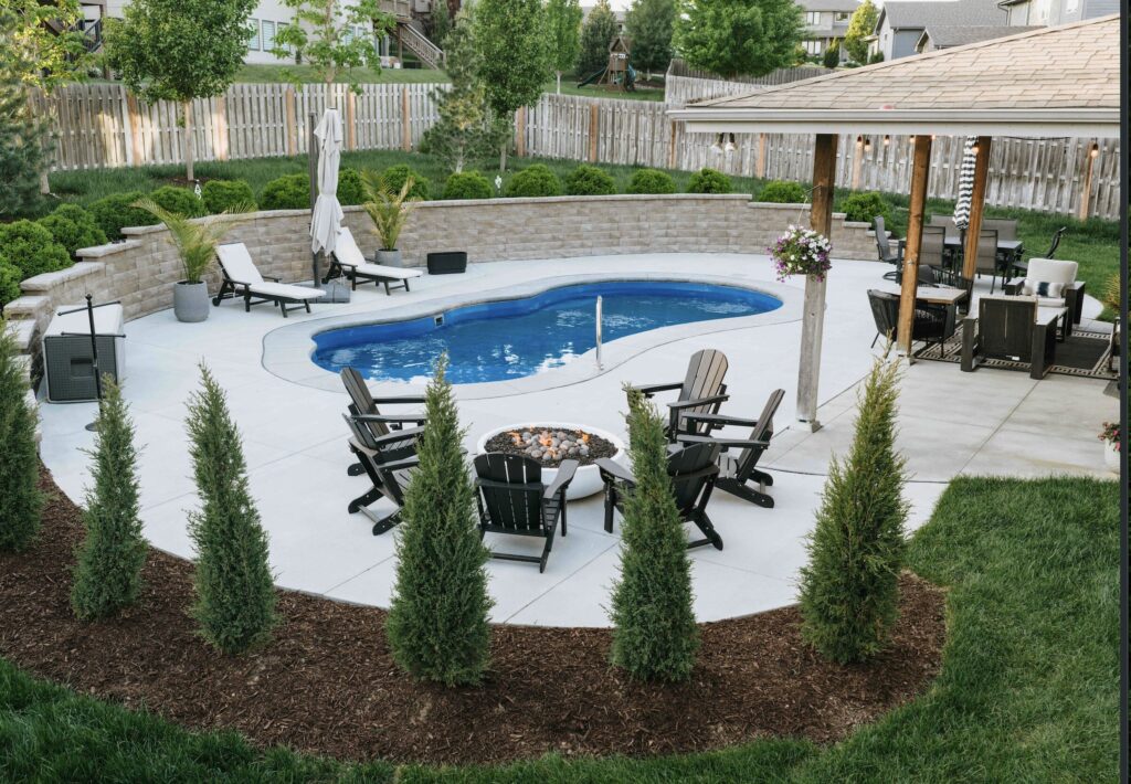 Curved freeform pool design surrounded by manicured lawn and stone paver coping