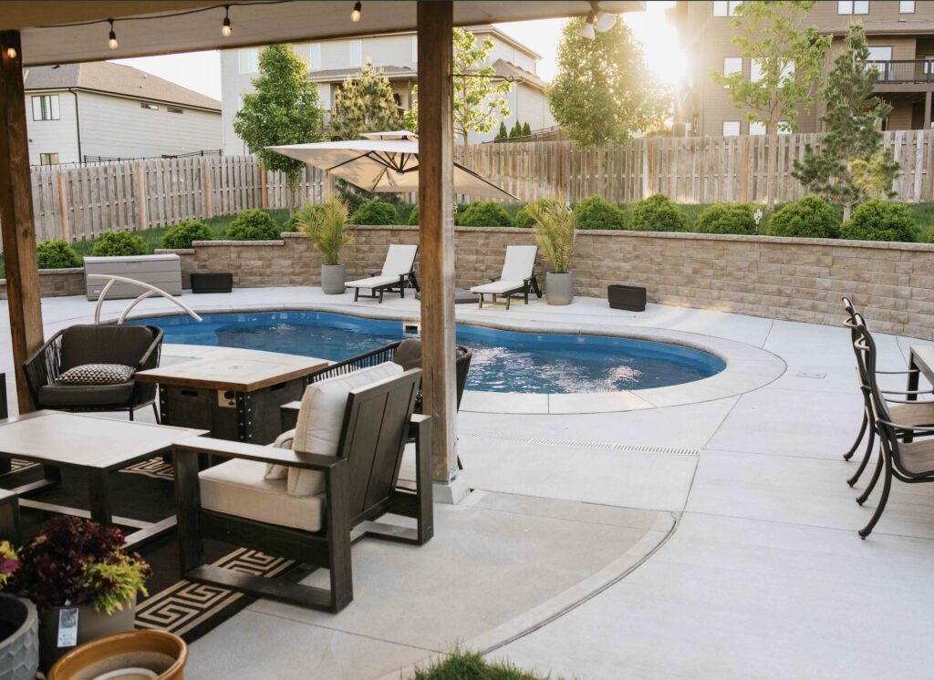 Covered patio lounge with fire pit overlooking inground pool and privacy fence
