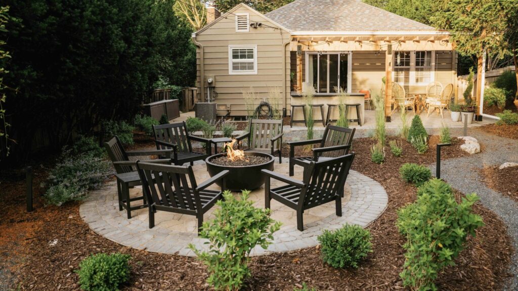Patio fire pit seating area with wooden pergola and surrounding landscape design