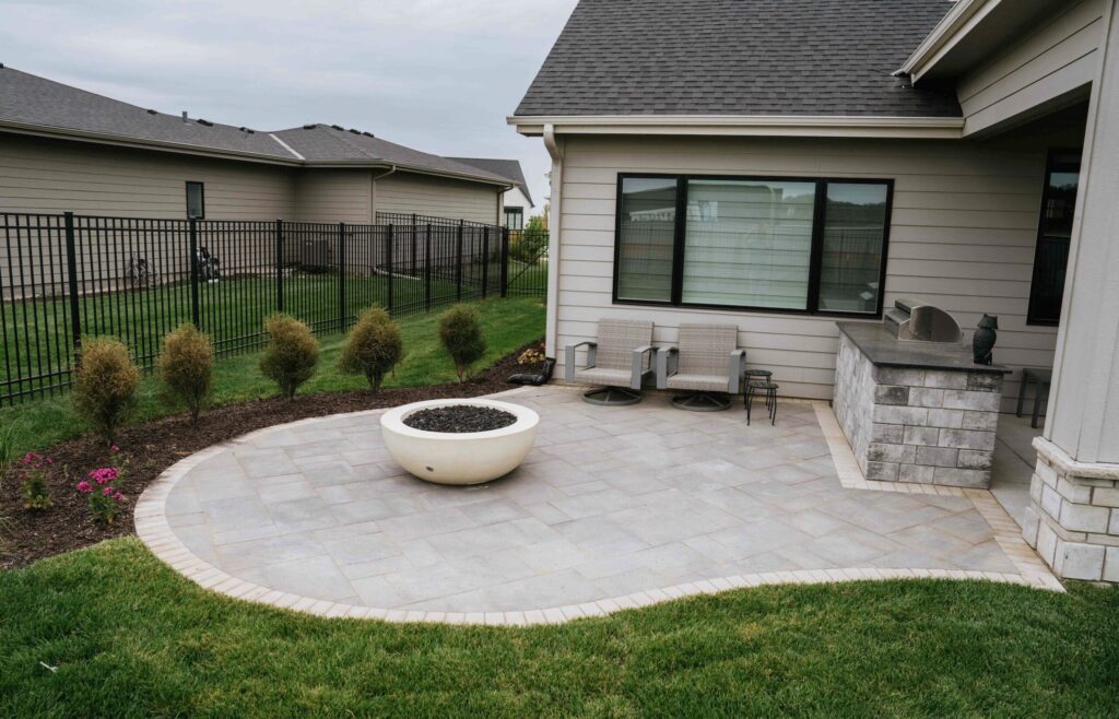 Backyard patio lounge area adjacent to home exterior with surrounding landscape beds