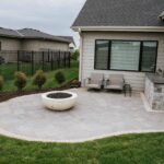 Backyard patio lounge area adjacent to home exterior with surrounding landscape beds