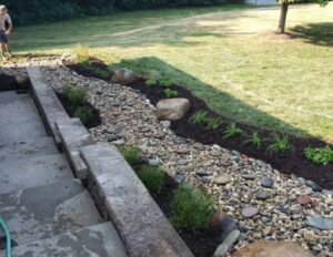 Landscape drainage channel with river rock directing water away from a residential property