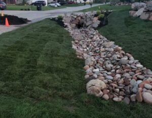 Rock-lined yard drainage channel designed to control stormwater runoff and prevent standing water