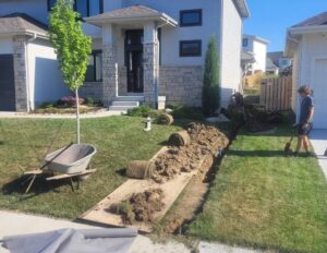 Residential yard drainage installation with a rock-lined channel directing water away from the home