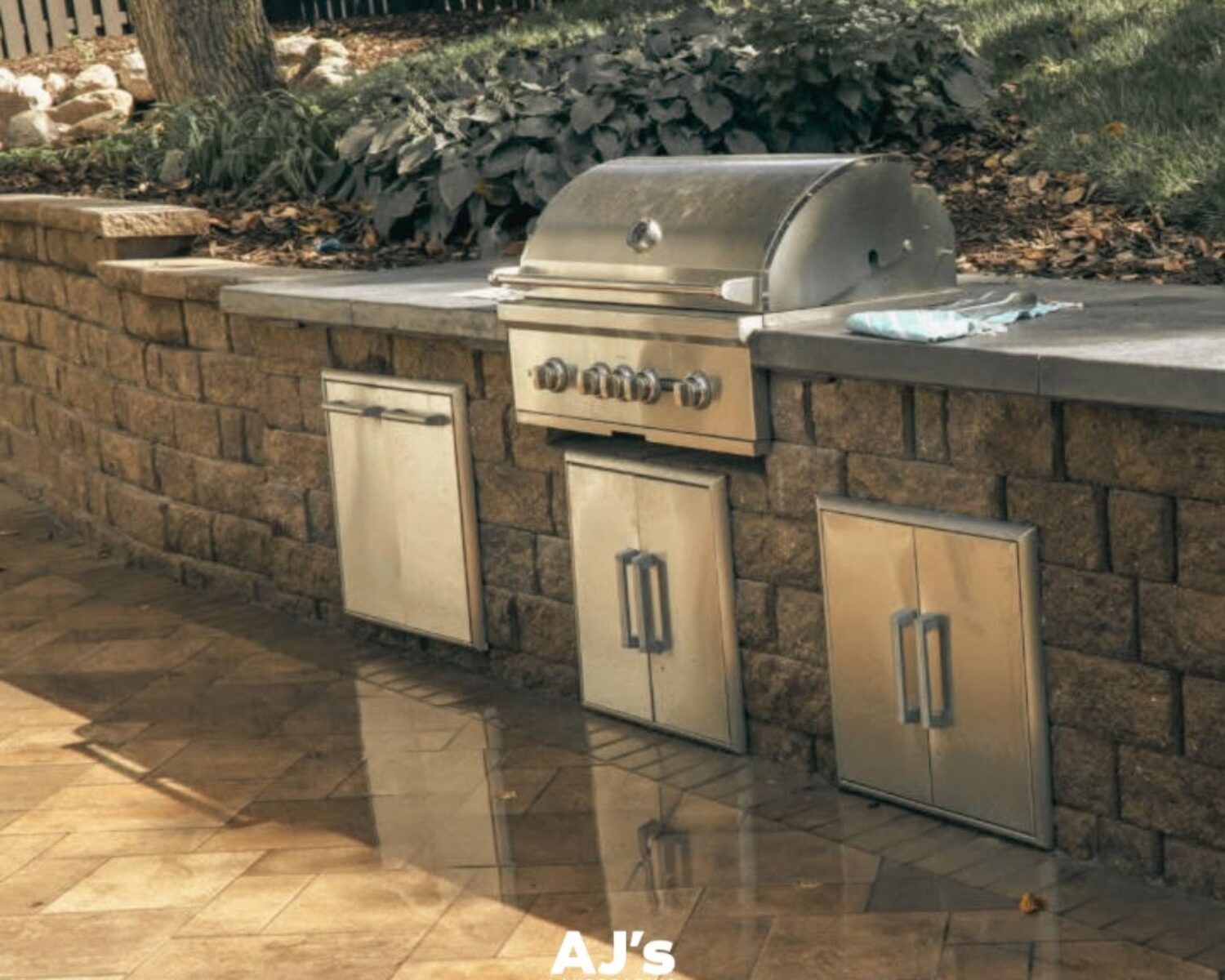 Built-in stainless steel grill and stone kitchen island by AJ's Landscaping in Omaha, NE