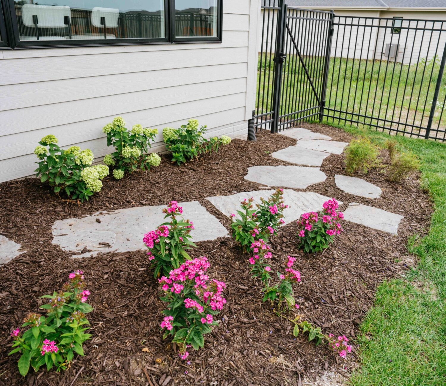 Landscaped garden bed with flowering plants, stone edging, and decorative rock