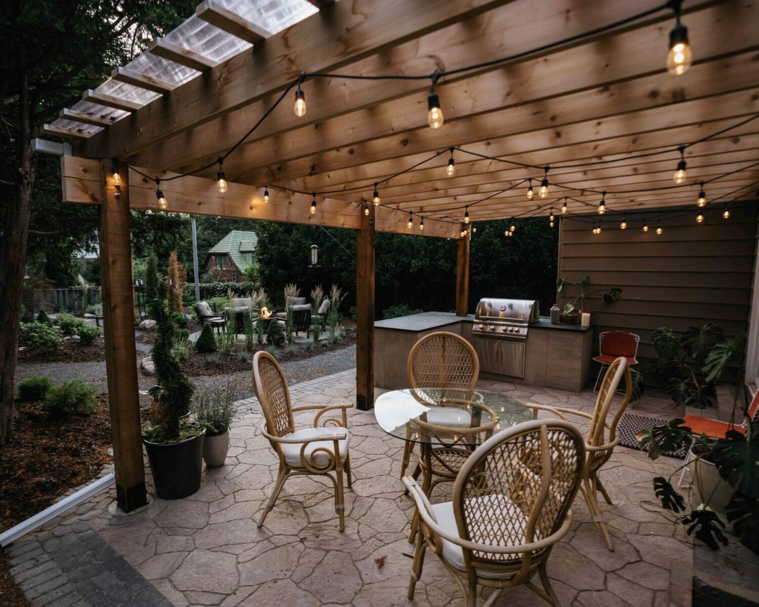 Custom wood pergola with string bistro lighting, patio seating, and built-in outdoor kitchen island