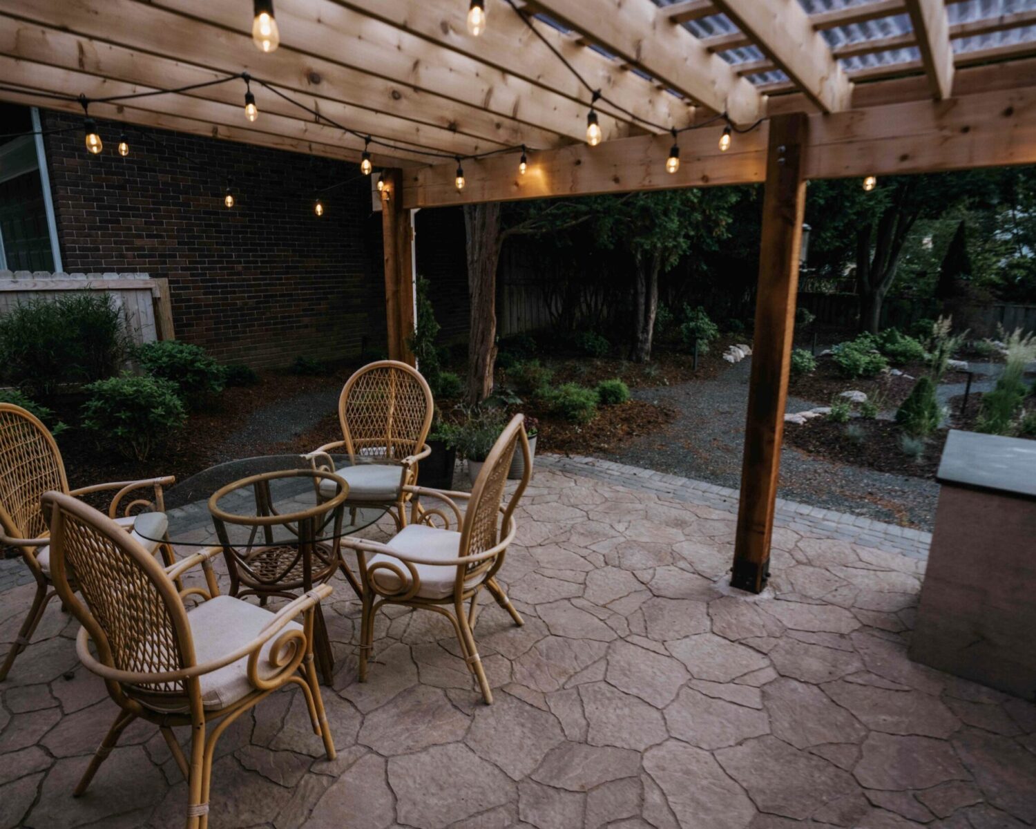 Custom wood pergola patio cover with bistro string lights and wicker chairs