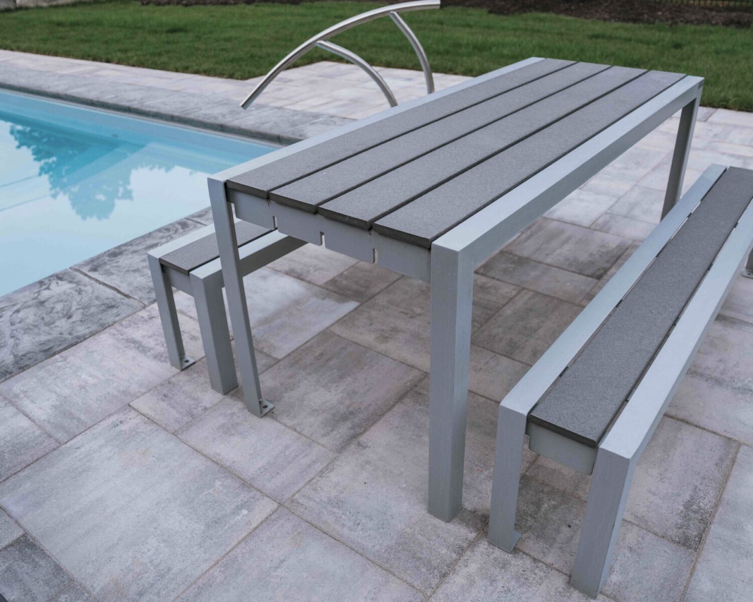 Modern outdoor dining table and bench set installed on concrete pool patio
