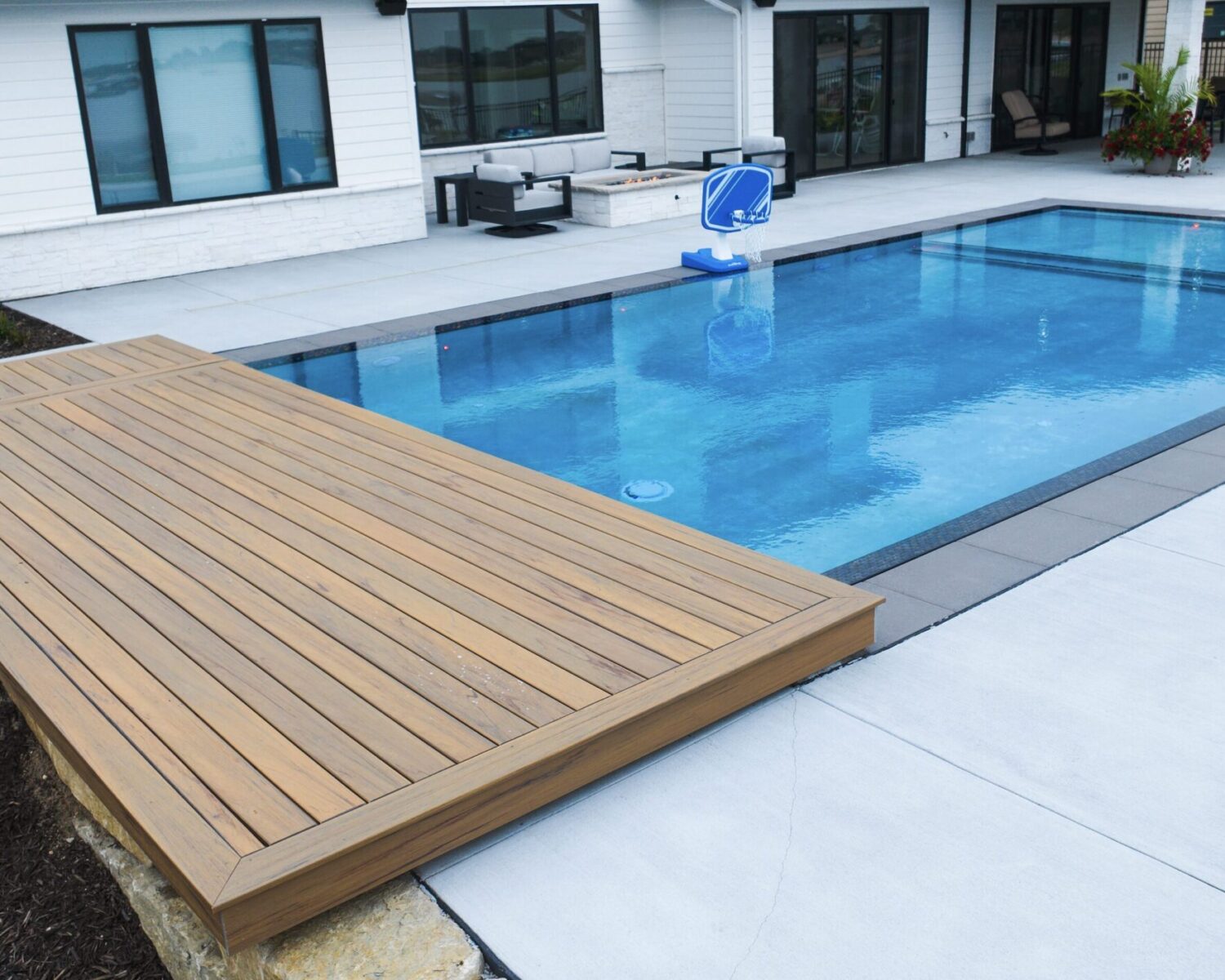 Modern rectangular inground swimming pool with wooden deck cover overlay built by custom pool contractor in Omaha area