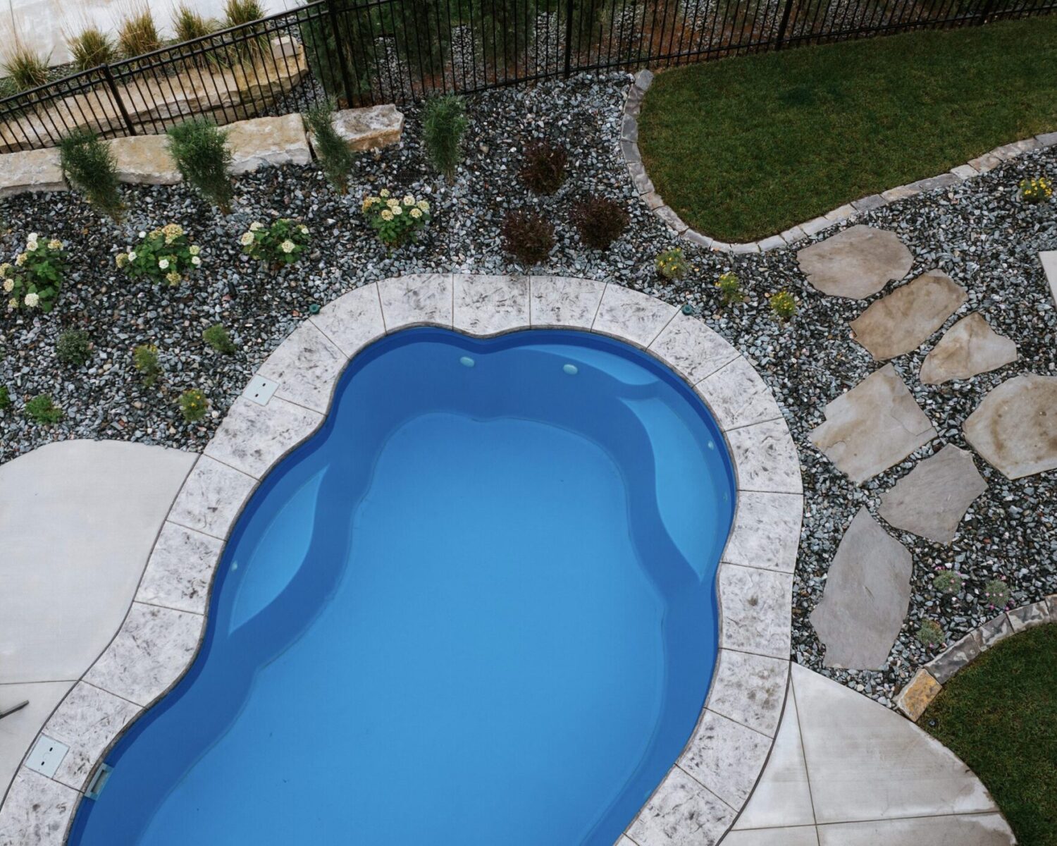 Custom freeform fiberglass pool installation surrounded by natural flagstone patio decking