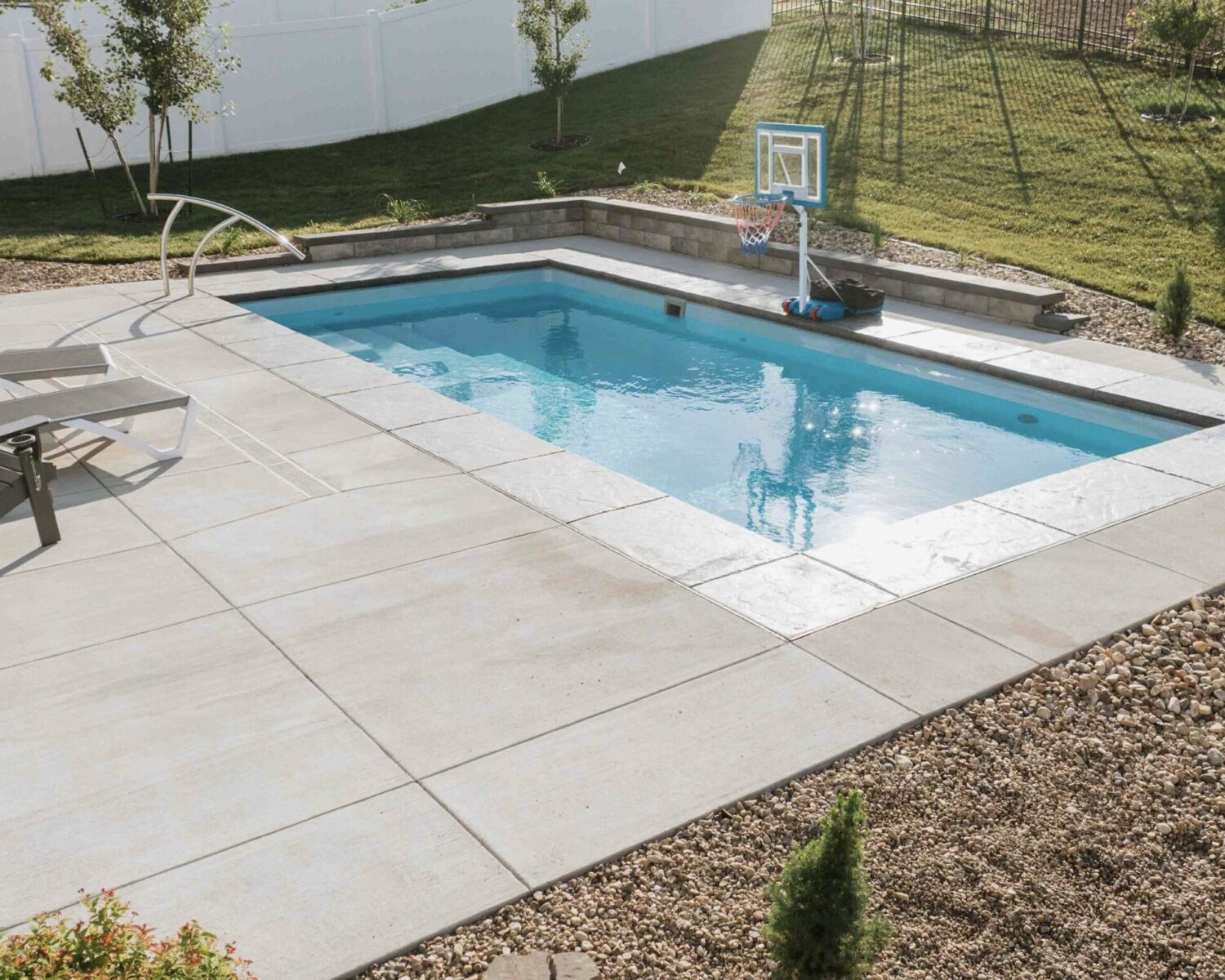 Rectangular inground pool design with smooth concrete coping and surrounding stone patio