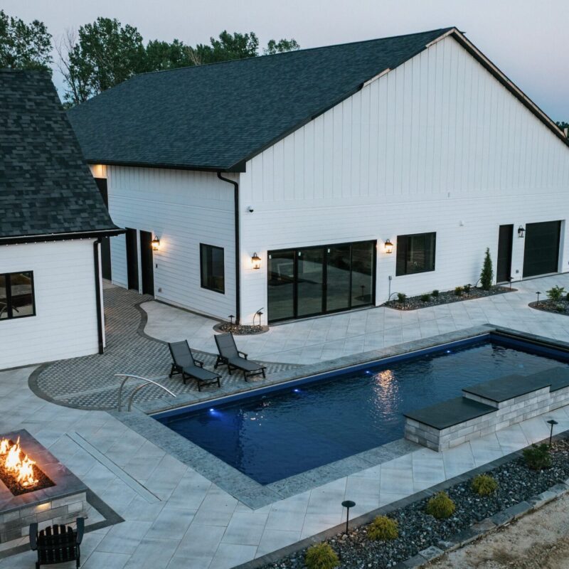 Modern backyard pool with spacious paved patio and outdoor living area