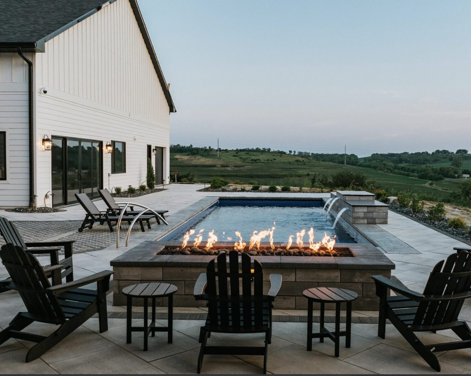 Modern backyard fire pit patio lounge overlooking scenic landscape at dusk