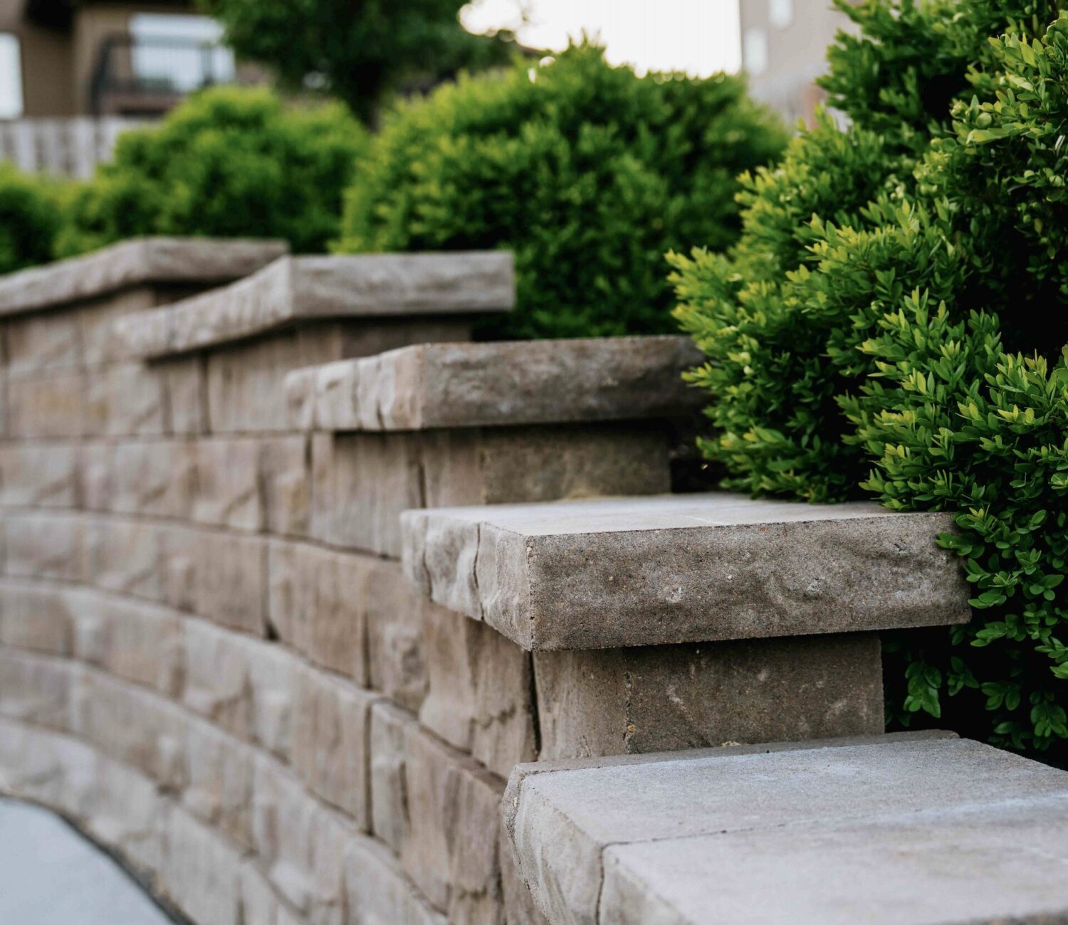 Tiered block retaining wall installation integrated with garden plant beds