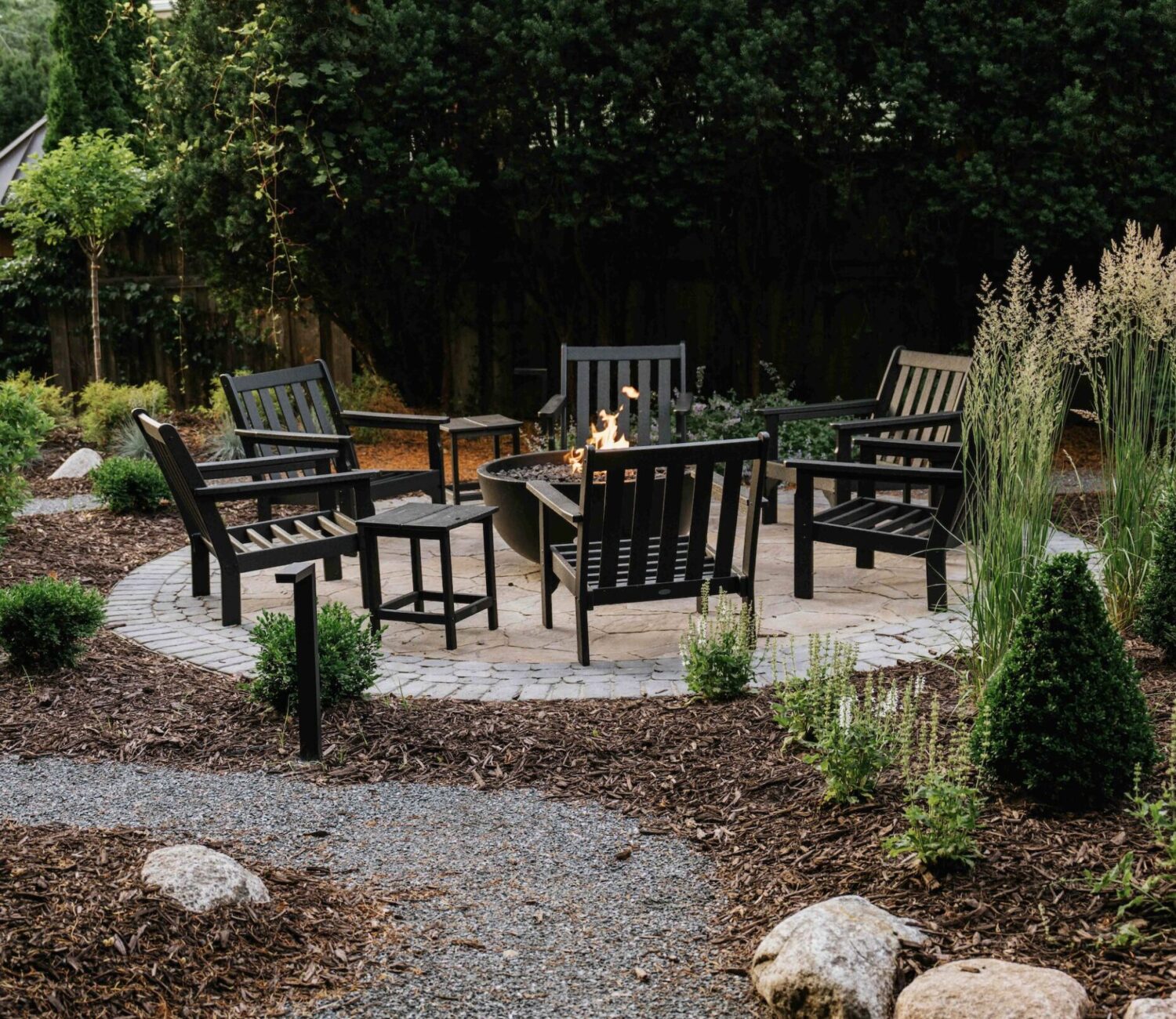 Patio seating area with black metal chairs surrounded by mulched garden borders