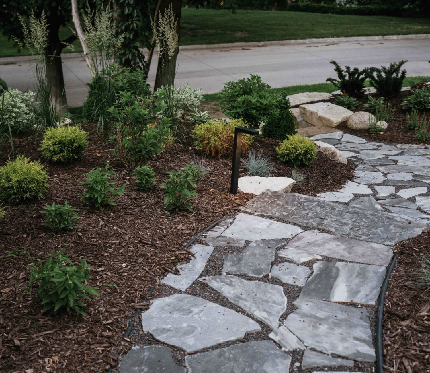 Stepping stone pathway through mulched side yard garden leading to backyard