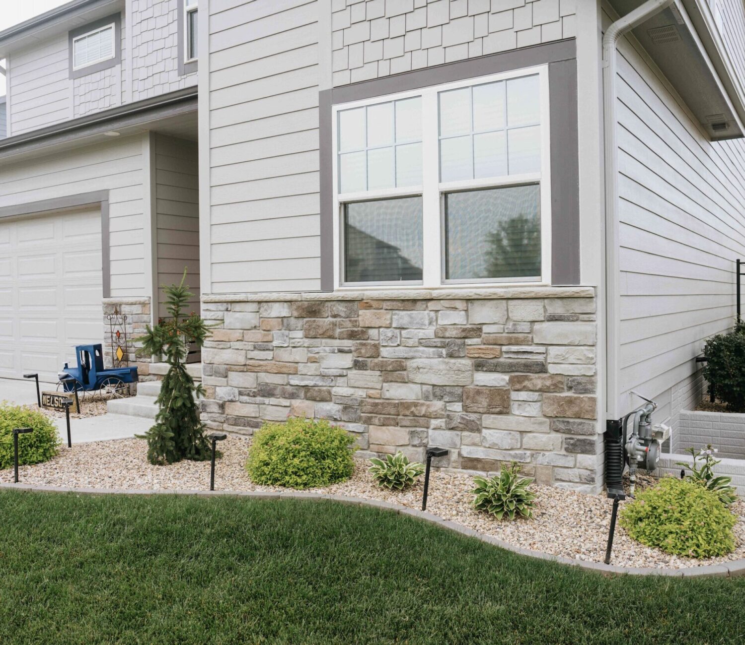 Modern home window exterior featuring stone veneer siding and simple foundation plantings