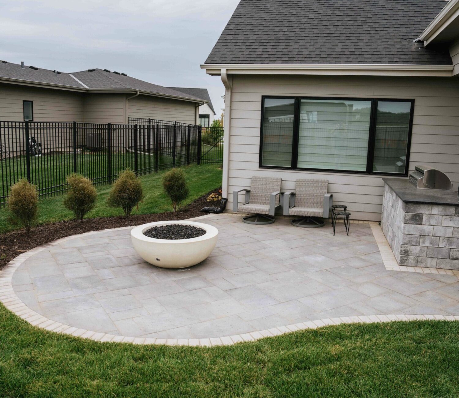 Backyard patio lounge area adjacent to home exterior with surrounding landscape beds